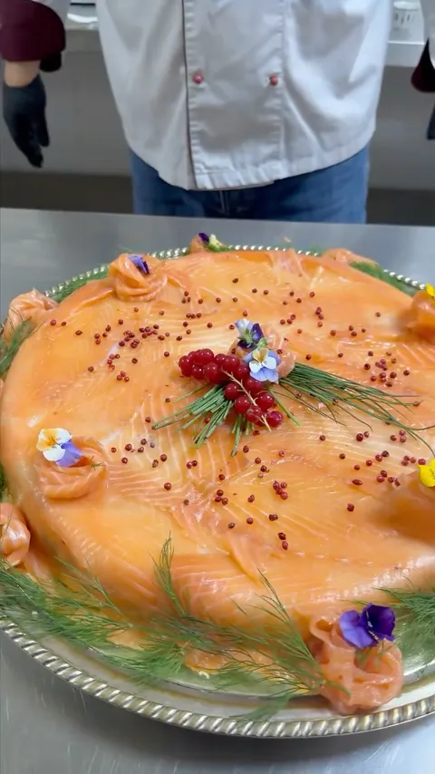 A smoked salmon centerpiece decorated by hand with herbs and edible flowers.